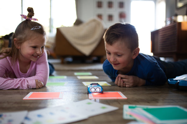 Two kids lie on the floor watching indi.