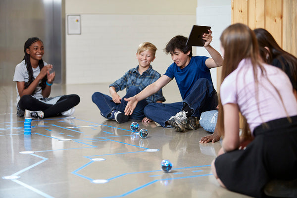 Students coding their BOLT+ robots through a maze made of tape.