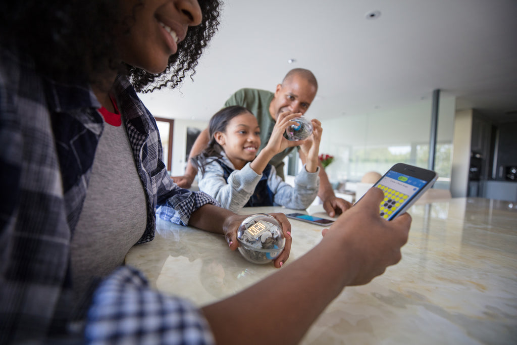 A family gathers around the kitchen table to learn how to program a Sphero BOLT for National Robotics Week.