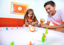Girl and boy playing with orange mini robots in a lane of pins and cones.