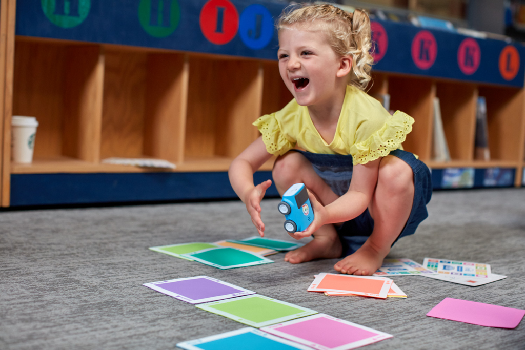 A young kid laughs while playing with Sphero indi.