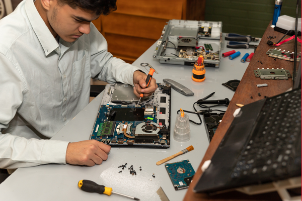 A man repairs electronics on a computer.