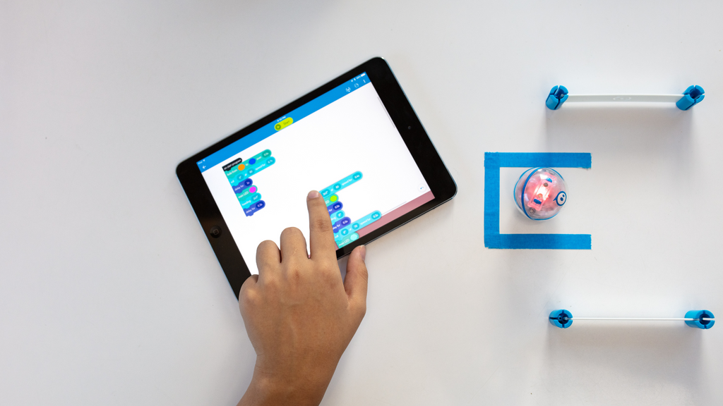 A person uses block coding for kids in the Sphero Edu app to program their Sphero Mini through a maze.