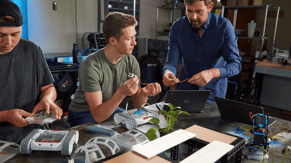 A high school teacher shows his student how to connect a sensor to a Sphero RVR+ robot.