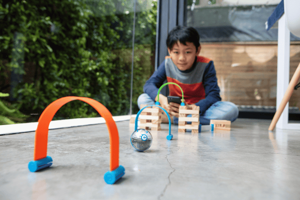 A kid drive a Sphero Mini through an obstacle course.