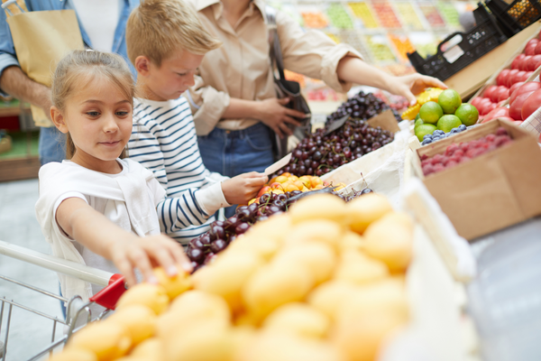 Two kids select fruit at the grocery store.