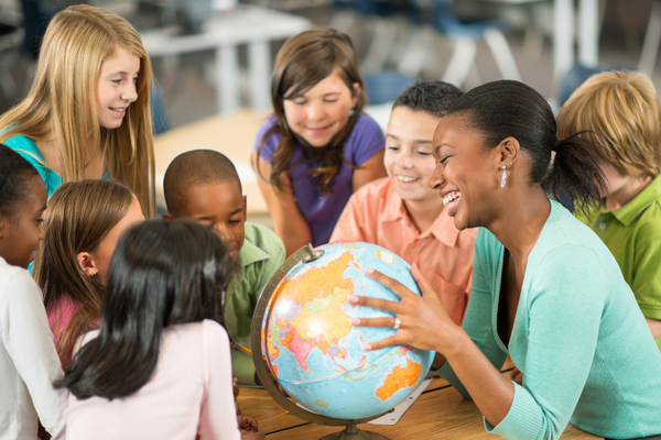 A teach shows students a globe.