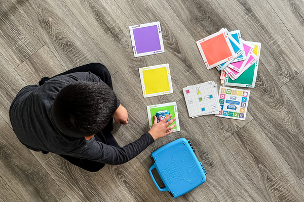 An overhead view of a child creating a path for indi on the floor.