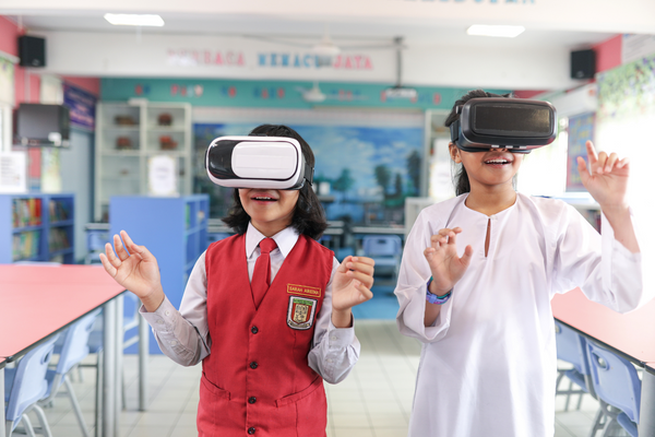 Two students wearing VR headsets in a classroom.